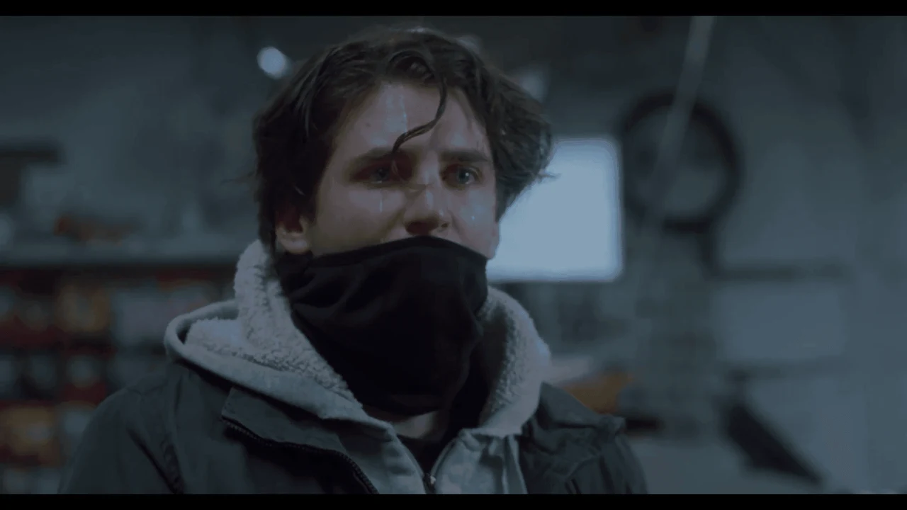 A person wearing a scarf over their face in a cool-toned scene from So Long.